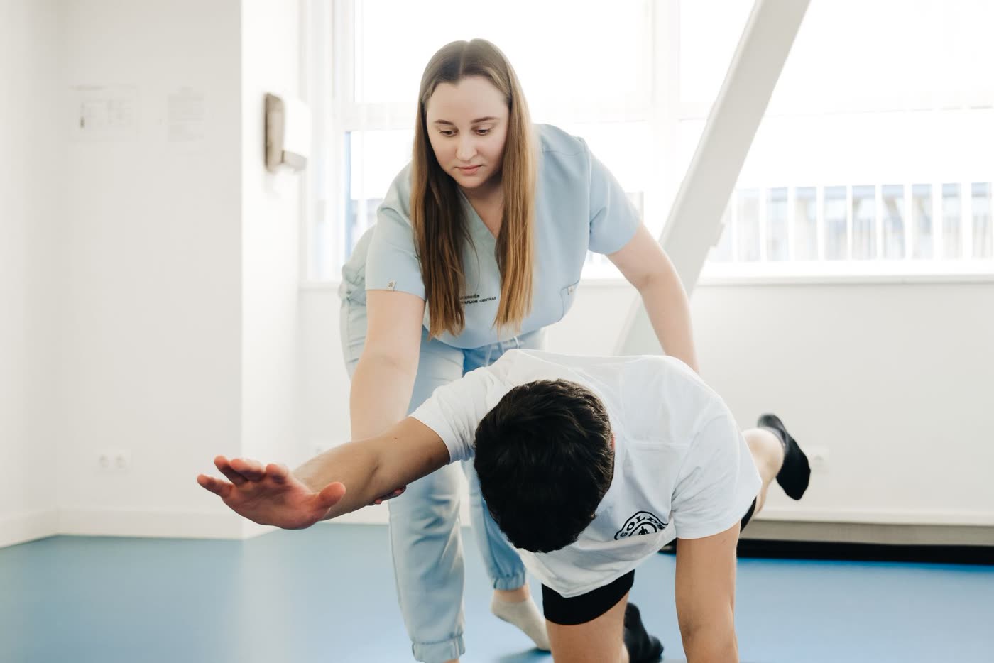 Therapeutin korrigiert einen Patienten bei einer Übung im hellen Trainingsraum