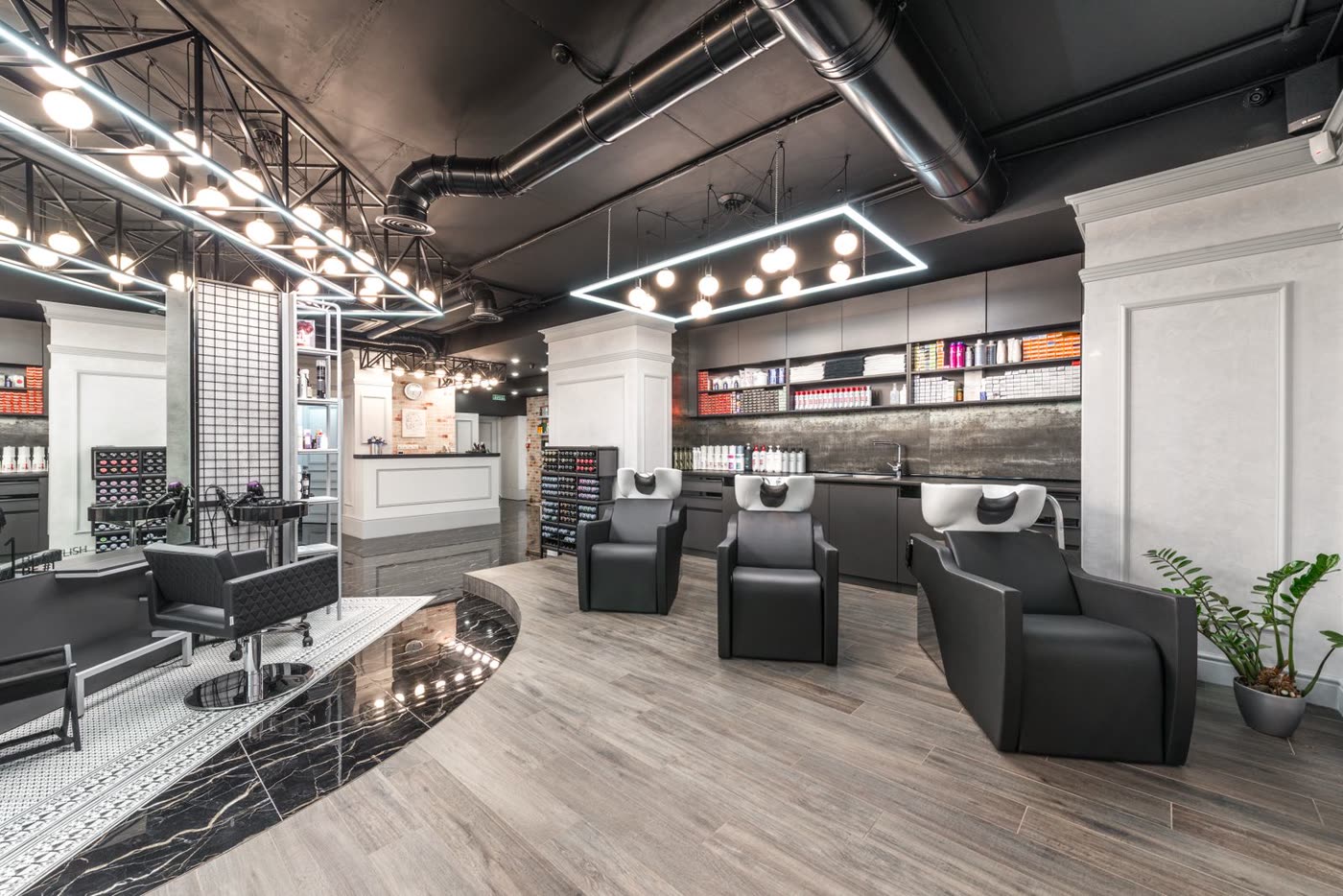 Drei Waschsessel in einem modernen Salon mit dunkler Decke und Holzboden